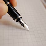 A detailed close-up of a fountain pen poised over graph paper, ideal for educational or business use.